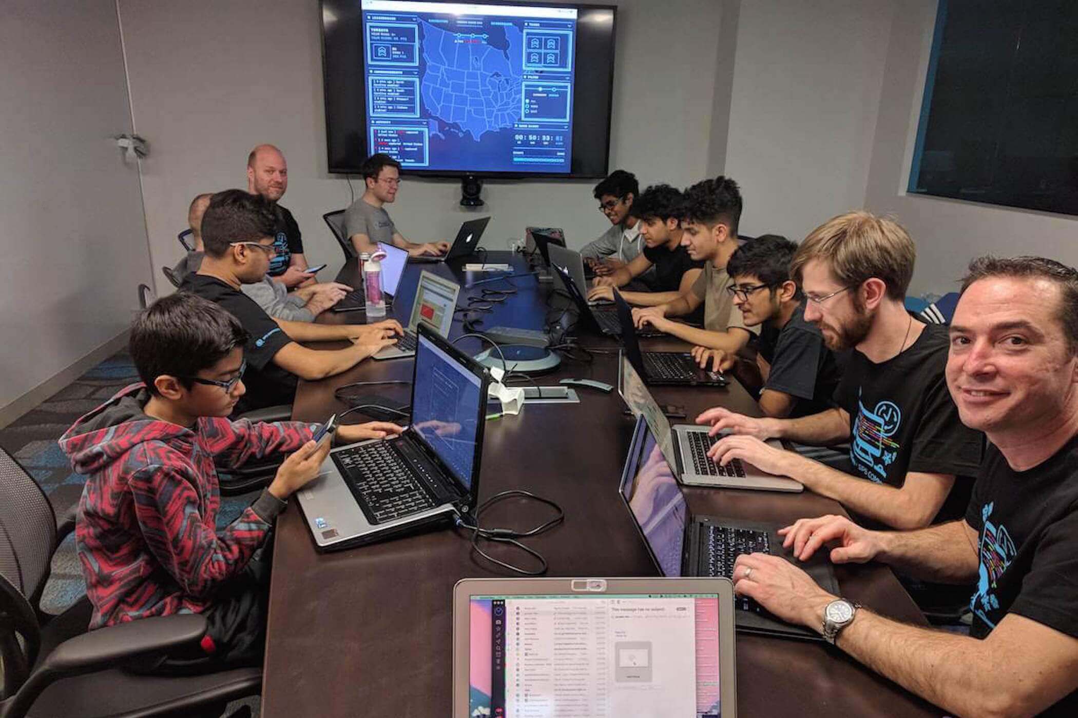 Students are gathered at a table competiting against other CodeDay events in a capture the flag competition.